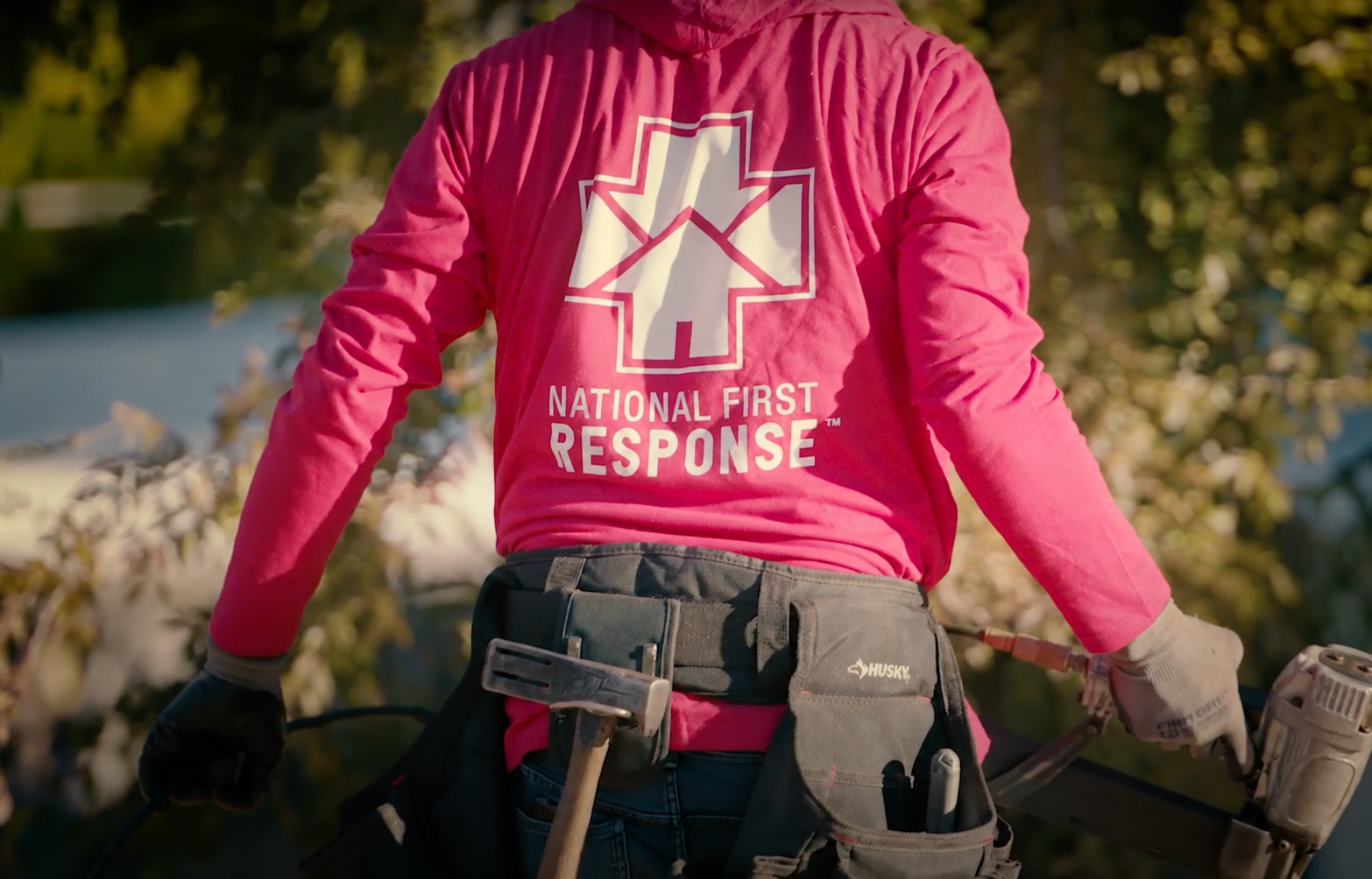 National First Response technician in a branded shirt with tool belt on site