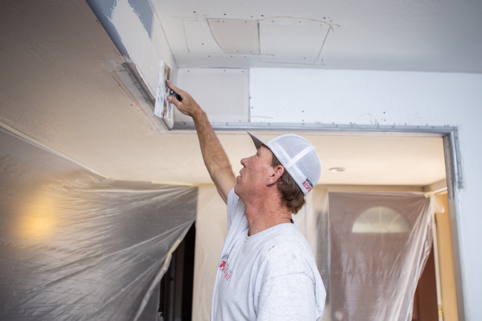Technician completing ceiling repairs after restoration
