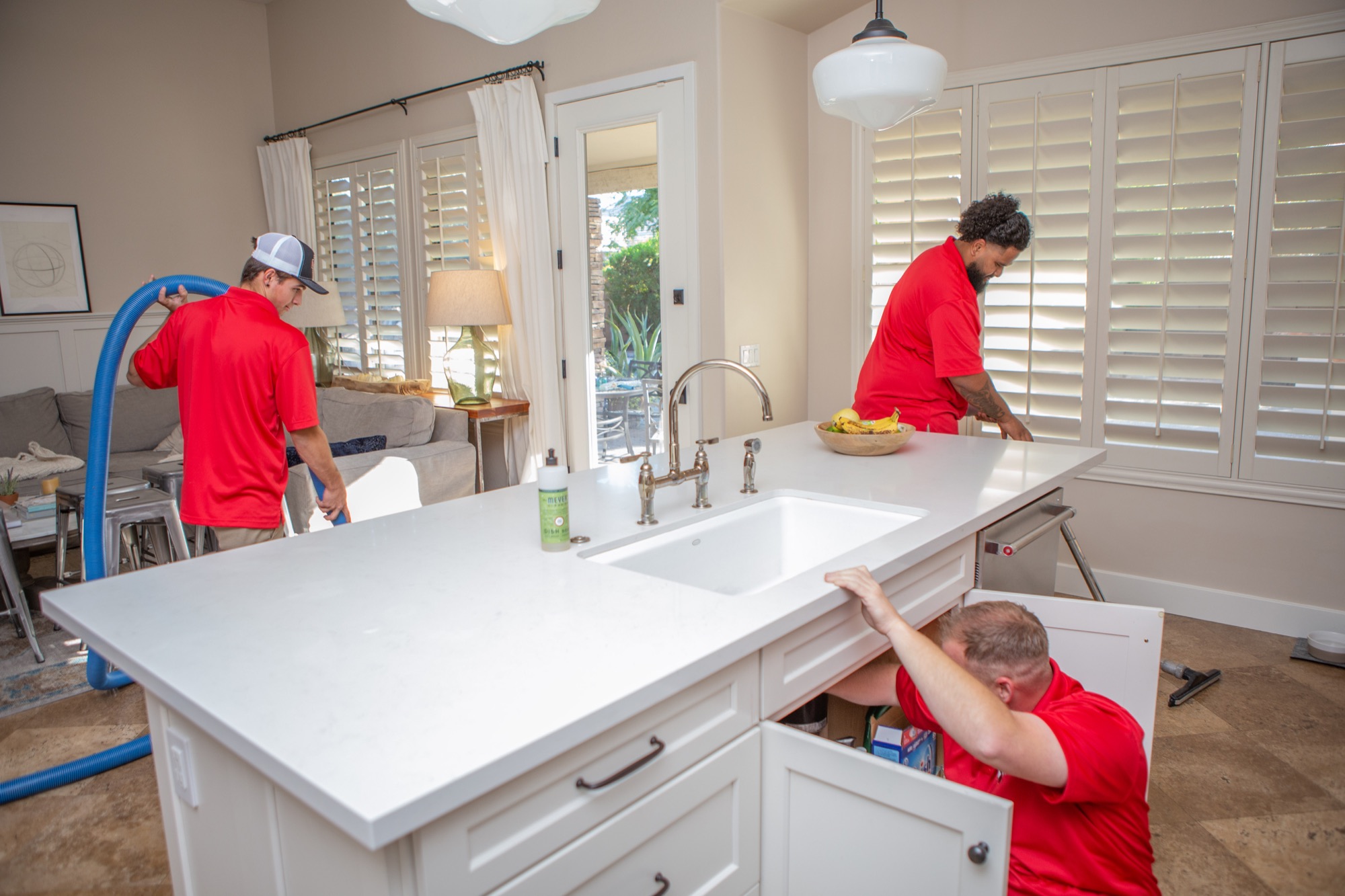 Technicians drying a kitchen and living area after a plumbing loss